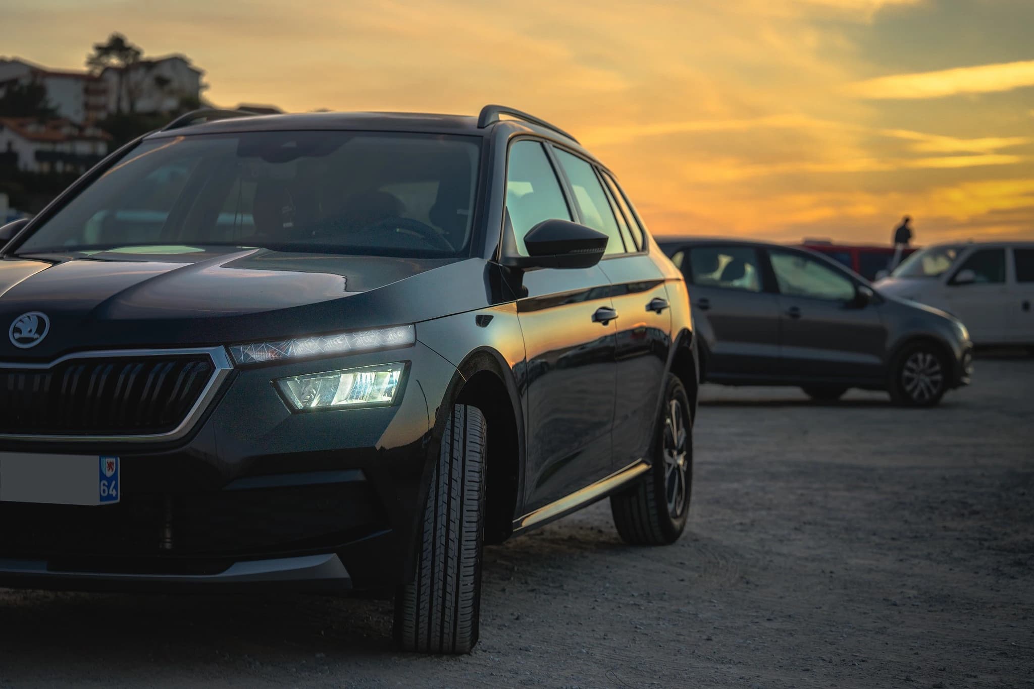 Skoda Kamiq vu de trois quarts, avec les reflets dorés du coucher du soleil sur la carrosserie.