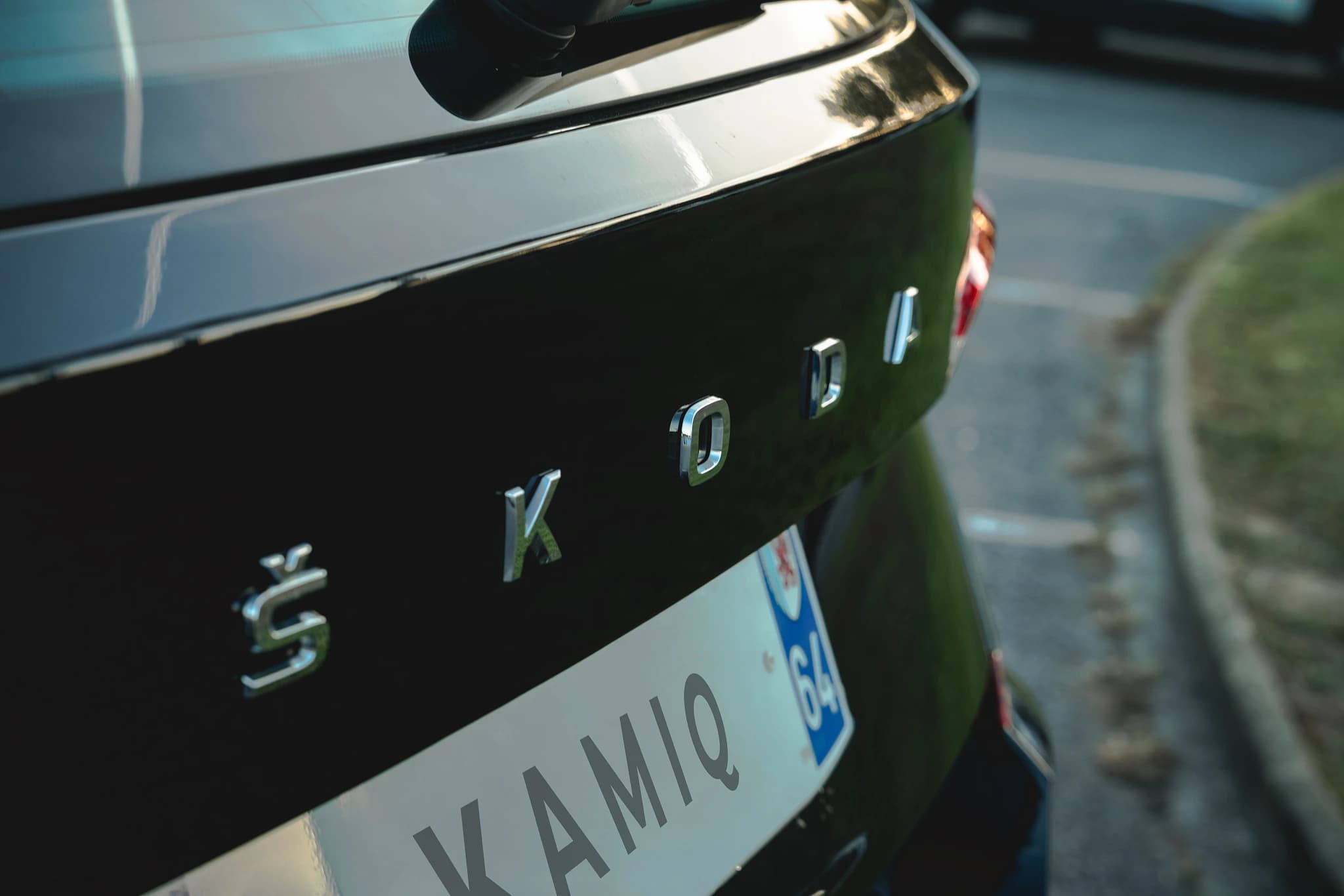 Détail du hayon du Skoda Kamiq et du lettrage chromé Škoda, dans la lumière de fin de journée.