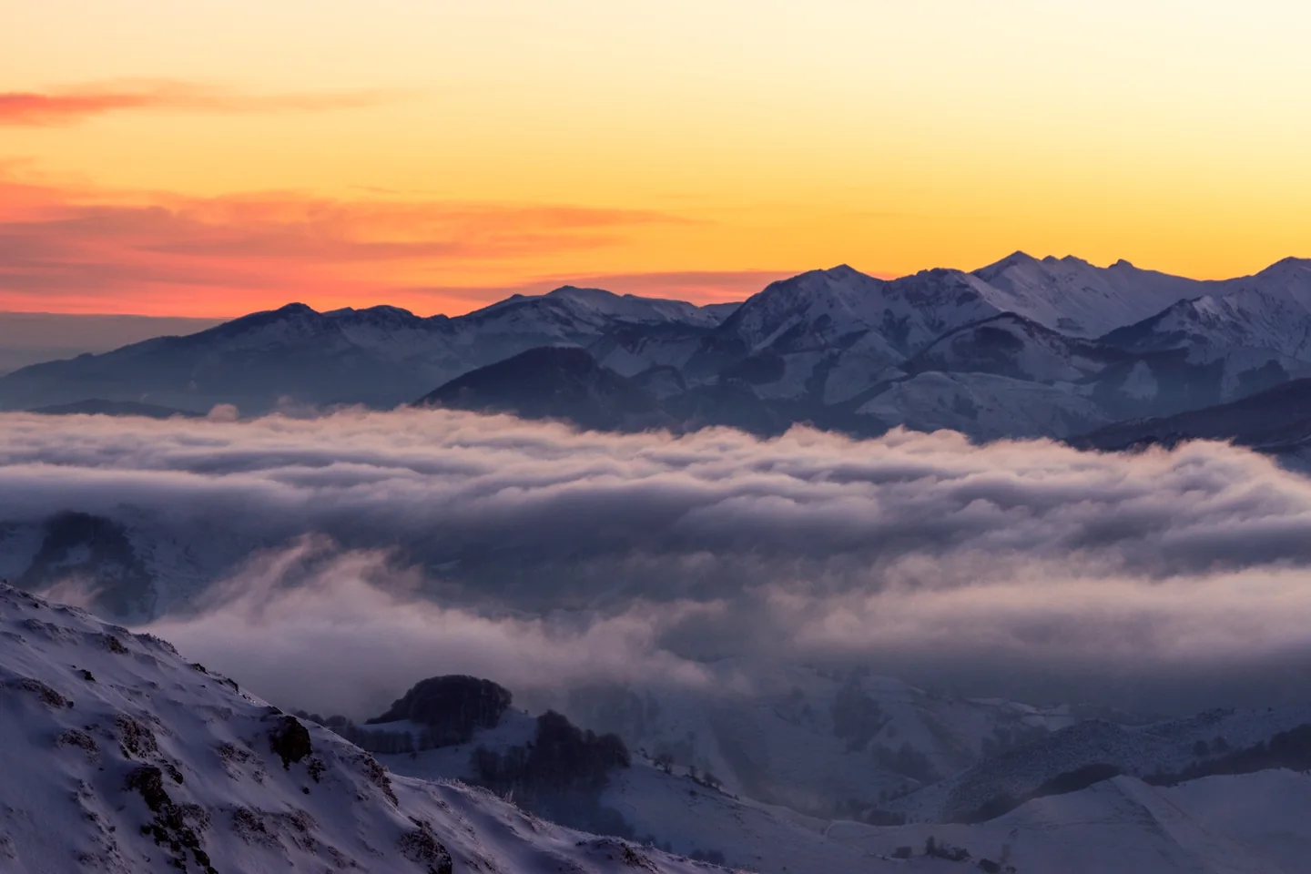 Paysage enneigé au-dessus d’une mer de nuages au lever du jour.
